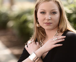 Image of attractive woman dressed in black wearing Blanca Flor sterling silver bracelet, rings, earings & necklace