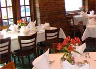 Image of fresh flowers, white tablecloths and original exposed brick in the front dining room of Chiapparelli's Restaurant Little Italy Baltimore MD