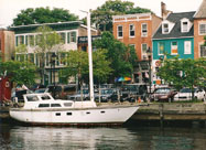 Serene image of white sialboat docked along historic old Belgian block Thames Street with its eclectic array of 18th century buildings that comprise the historic maritime community of Fell's Point, Baltimore, MD
